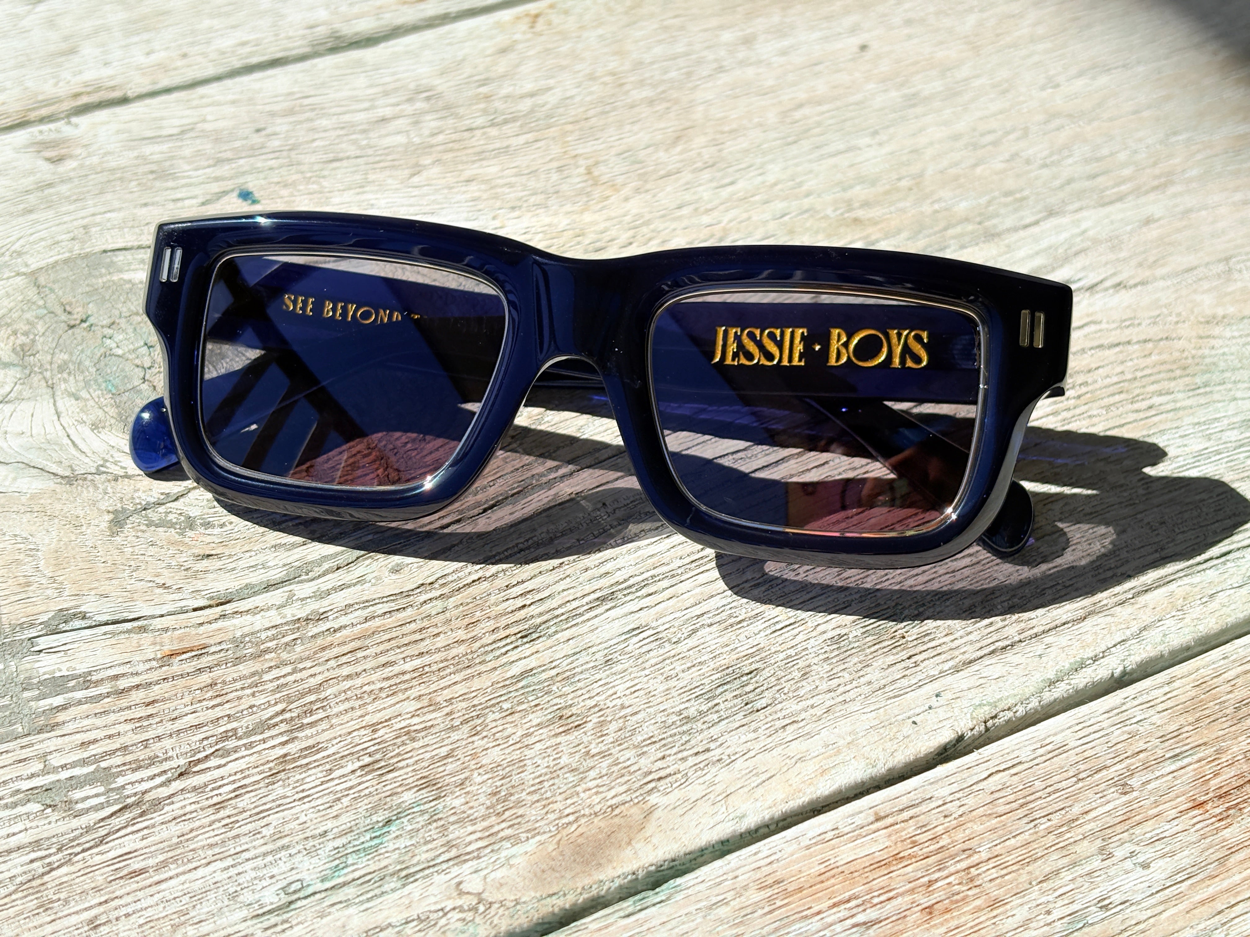 Blue sunglasses with 'JESSE BOYS' branding on